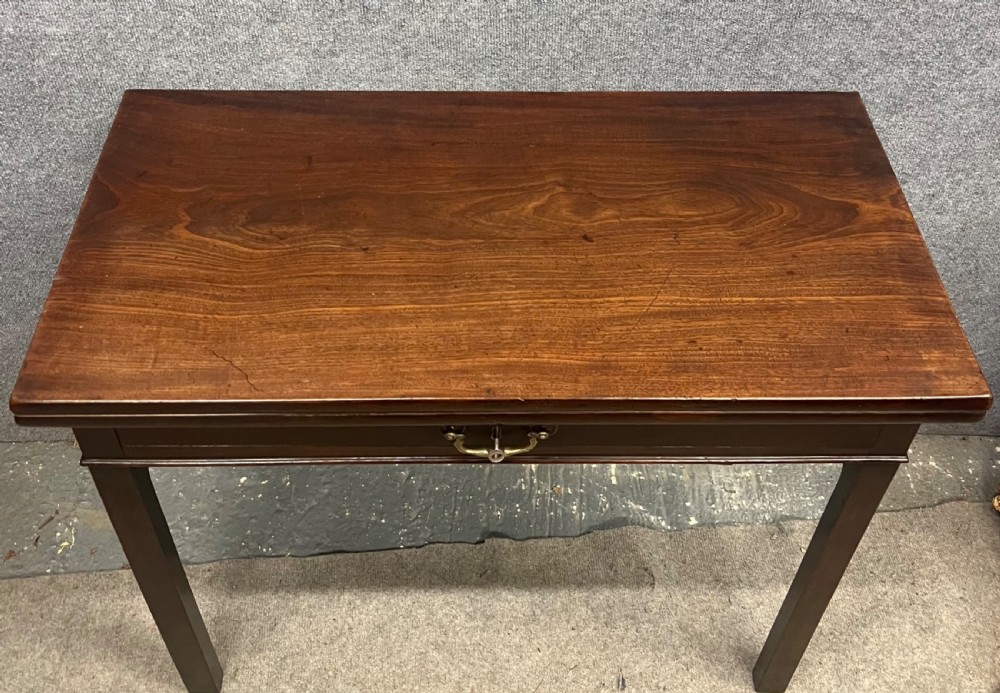 A Georgian dark mahogany fold-over table with straight square legs and a central brass swan-neck handle. View X