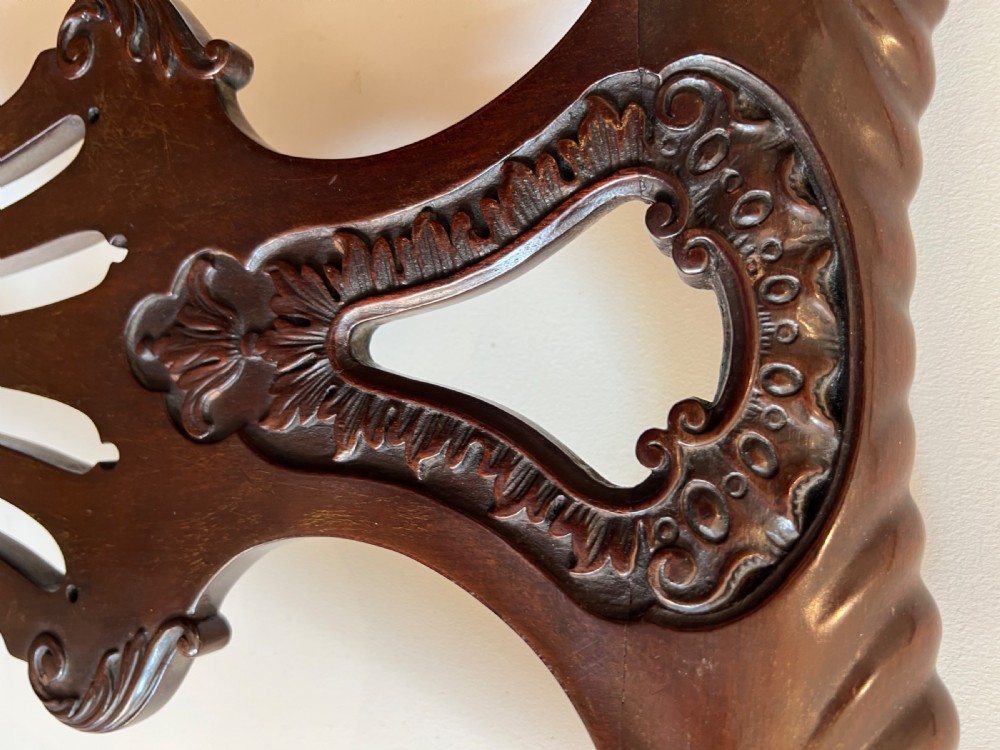 An 18th-century dark mahogany Chippendale armchair featuring a pierced carved back splat, curved arms, floral upholstered seat, and carved cabriole legs. View IV
