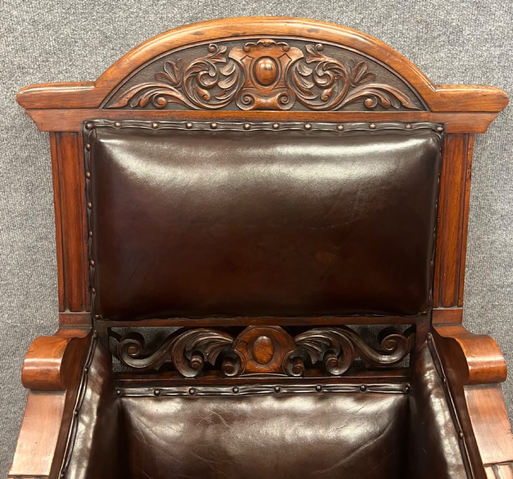 A pair of carved walnut high-back armchairs upholstered in dark brown leather with stud detailing and brass castors. View IV