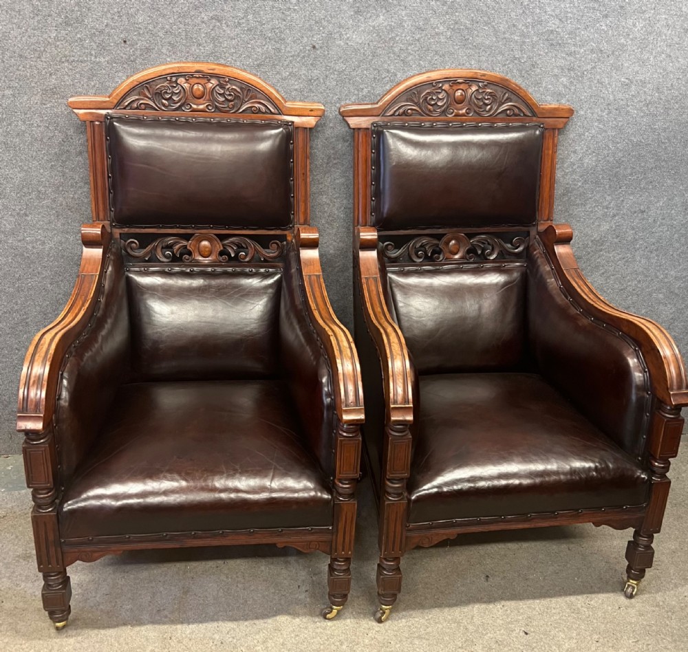 A pair of carved walnut high-back armchairs upholstered in dark brown leather with stud detailing and brass castors. View VIII