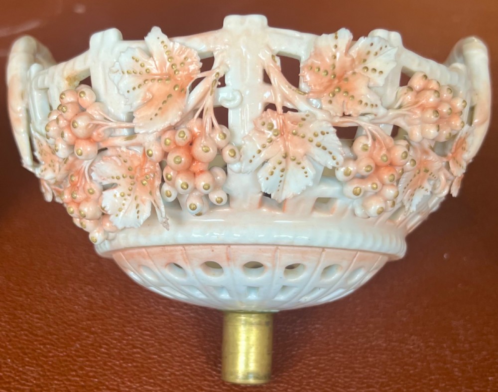 A pair of antique white and peach porcelain centrepiece comports with reticulated lattice baskets, floral applique, and moulded Rococo figures at the pedestals. View X