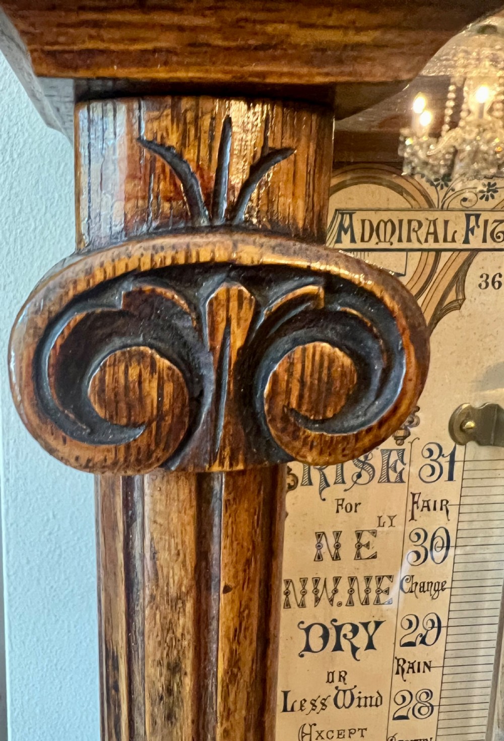A 19th-century carved oak Admiral Fitzroy wall barometer featuring architectural details, an arched cresting, and a detailed paper weather register. View V