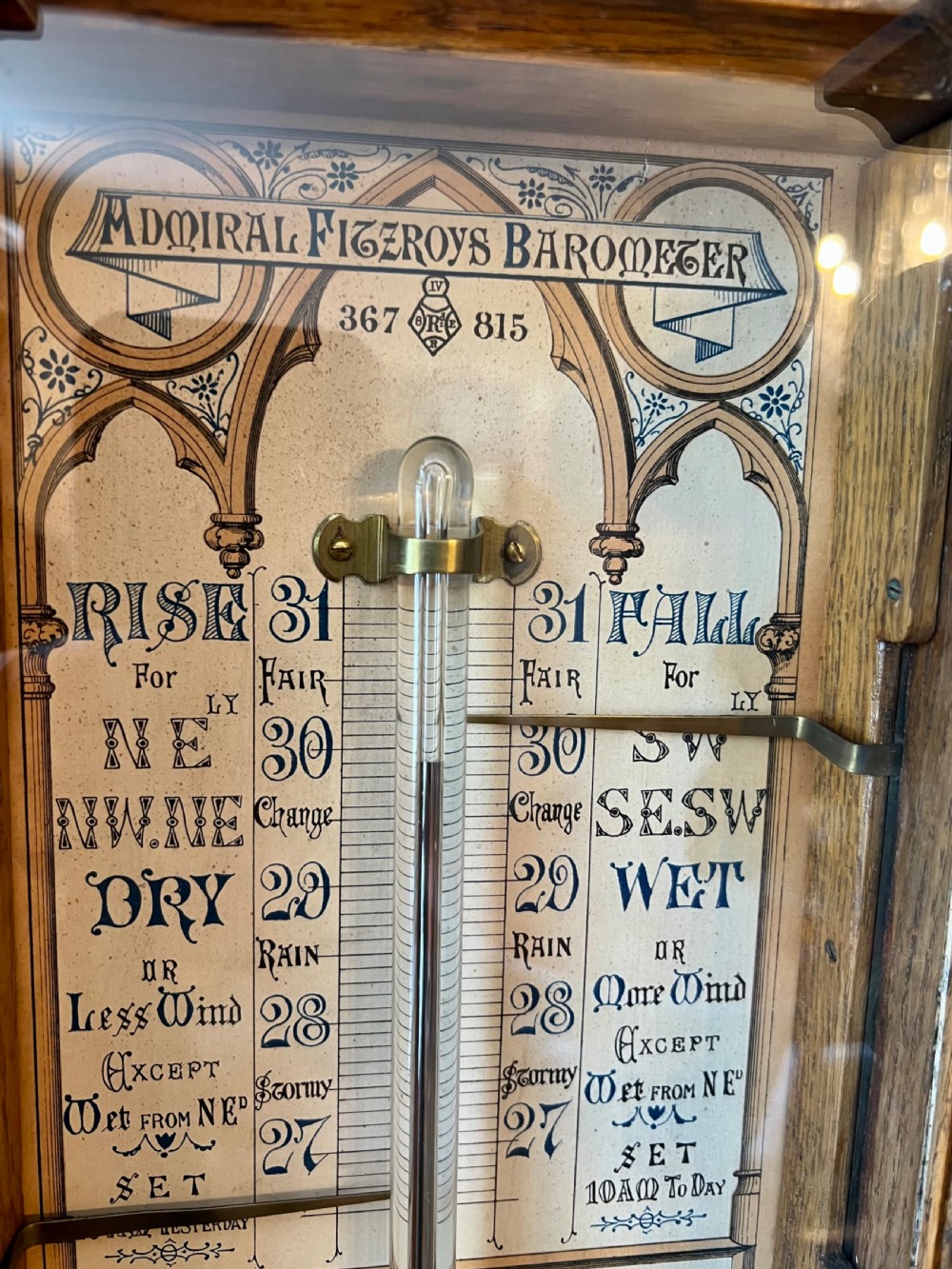A 19th-century carved oak Admiral Fitzroy wall barometer featuring architectural details, an arched cresting, and a detailed paper weather register. View VIII