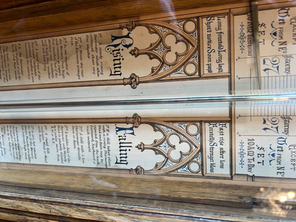 A 19th-century carved oak Admiral Fitzroy wall barometer featuring architectural details, an arched cresting, and a detailed paper weather register. View X