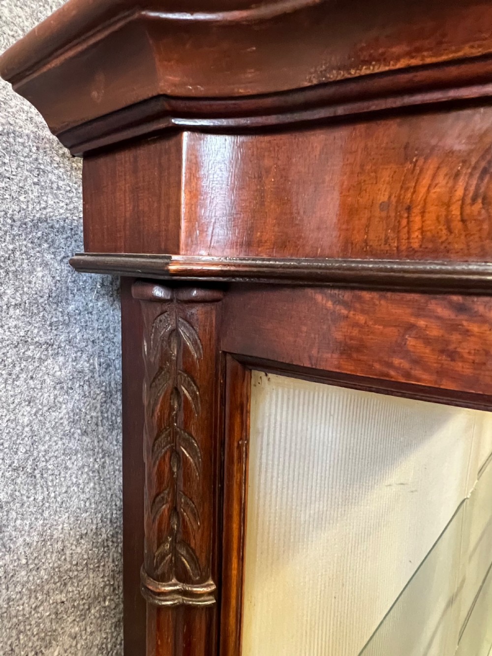 An Edwardian burr walnut display cabinet featuring curved glass side panels, an astragal glazed central door, glass shelves, and cabriole legs. View VI