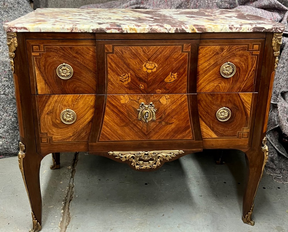 A nineteenth-century French Louis XV style commode with a contoured marble top, intricate floral marquetry, twin drawers, and cast gilt-bronze ormolu mounts.