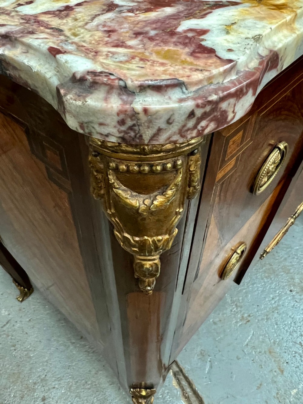 A nineteenth-century French Louis XV style commode with a contoured marble top, intricate floral marquetry, twin drawers, and cast gilt-bronze ormolu mounts. View VIII
