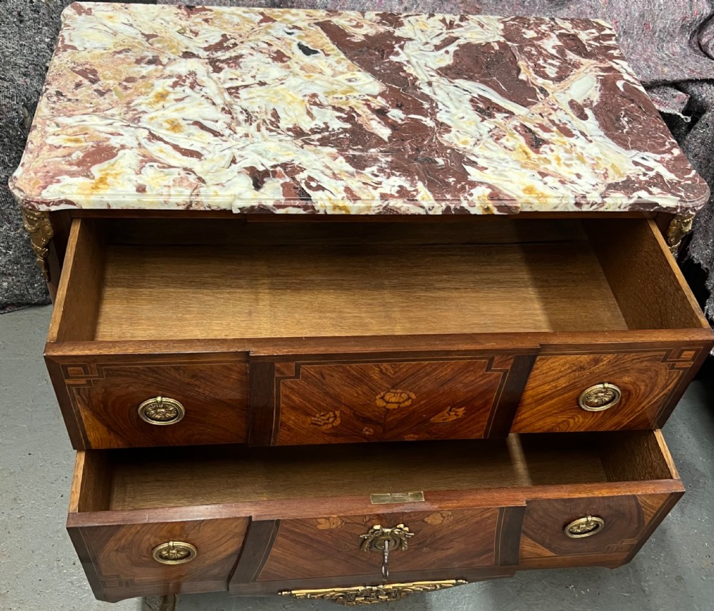A nineteenth-century French Louis XV style commode with a contoured marble top, intricate floral marquetry, twin drawers, and cast gilt-bronze ormolu mounts. View XI