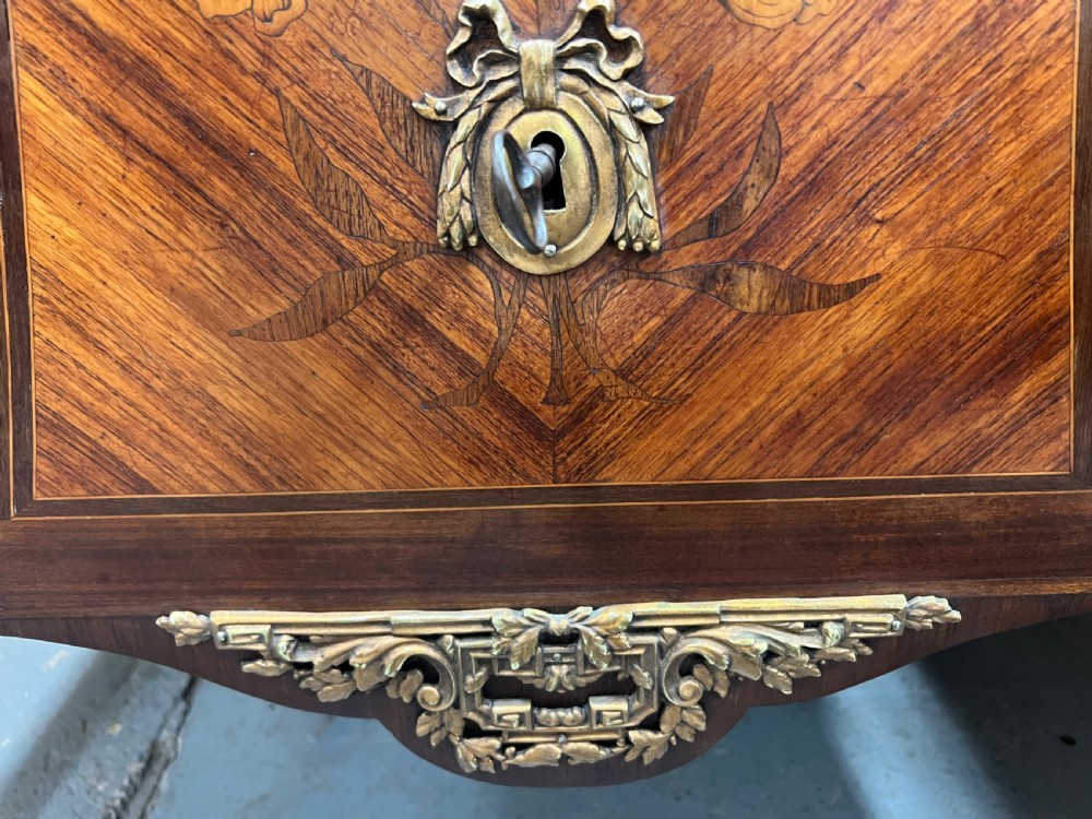 A nineteenth-century French Louis XV style commode with a contoured marble top, intricate floral marquetry, twin drawers, and cast gilt-bronze ormolu mounts. View XV