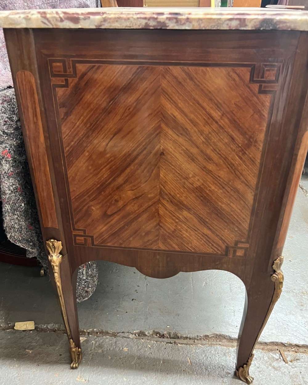 A nineteenth-century French Louis XV style commode with a contoured marble top, intricate floral marquetry, twin drawers, and cast gilt-bronze ormolu mounts. View XVI
