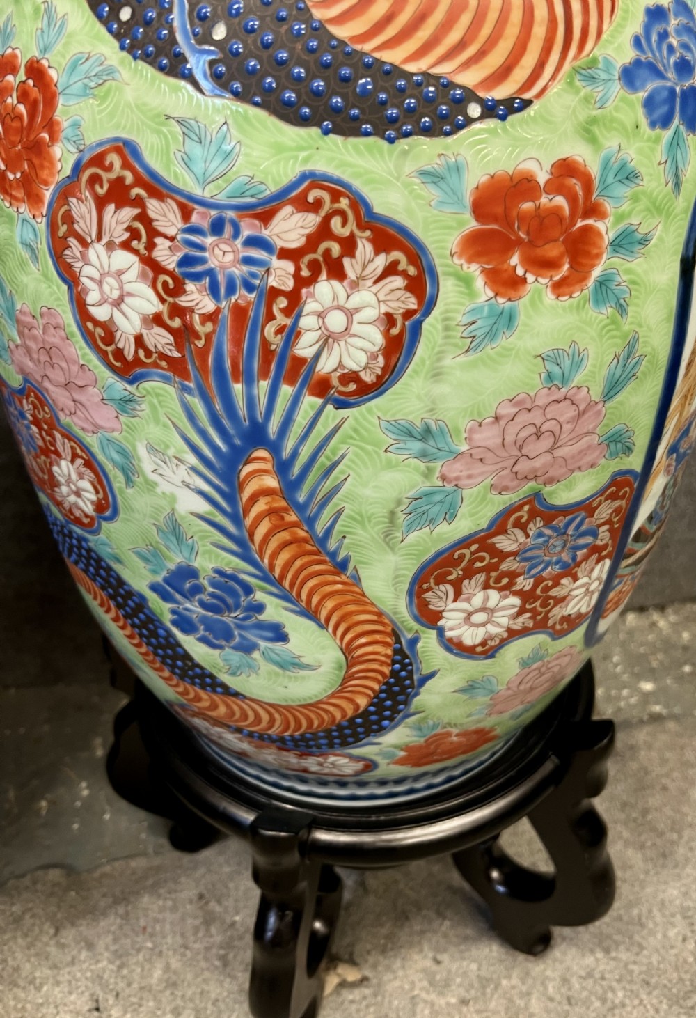 A pair of large, baluster-shaped Arita porcelain floor vases decorated with polychrome figures, floral motifs, and dragons, supported on carved dark wood bases. View VII