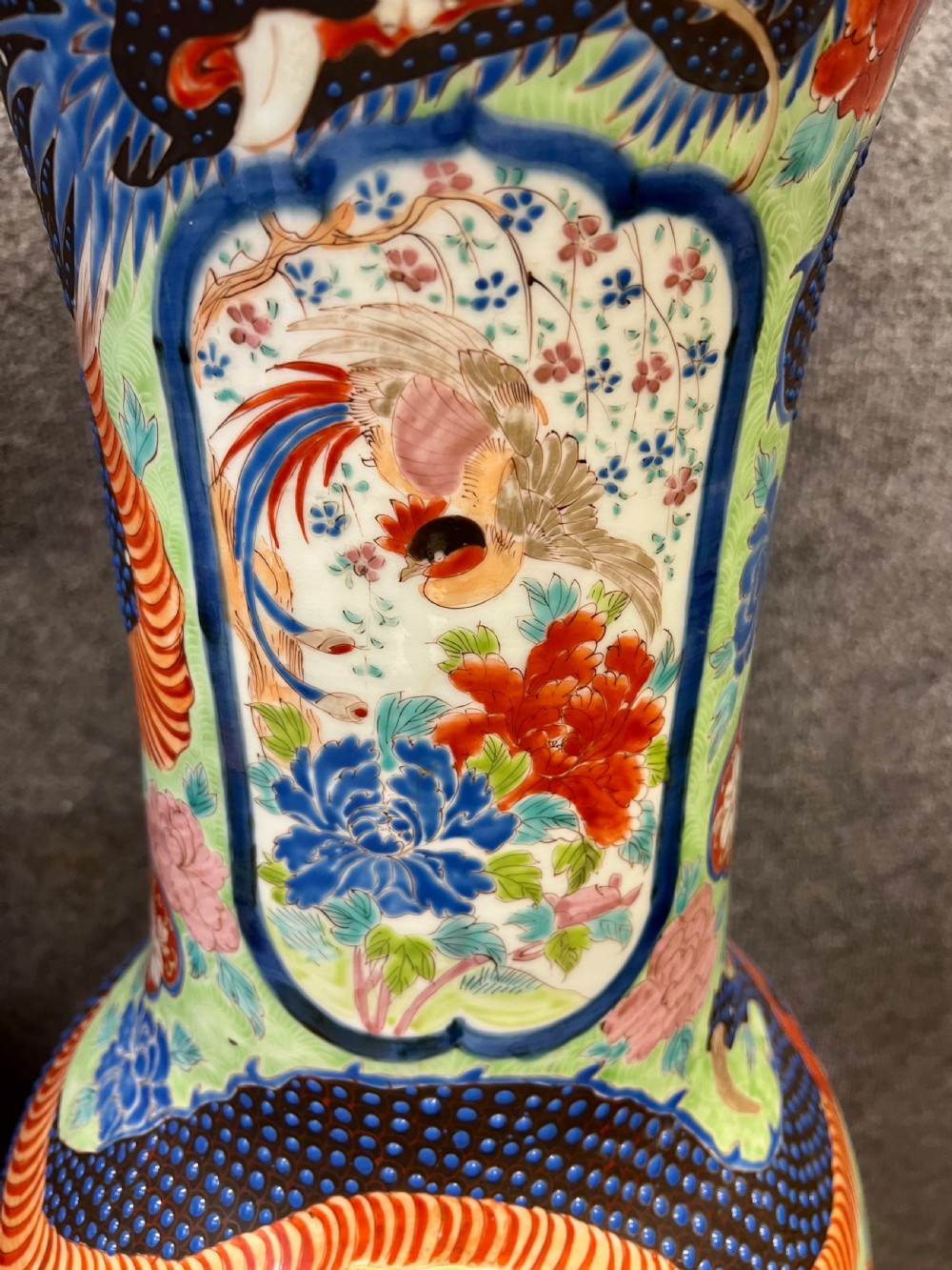 A pair of large, baluster-shaped Arita porcelain floor vases decorated with polychrome figures, floral motifs, and dragons, supported on carved dark wood bases. View VIII
