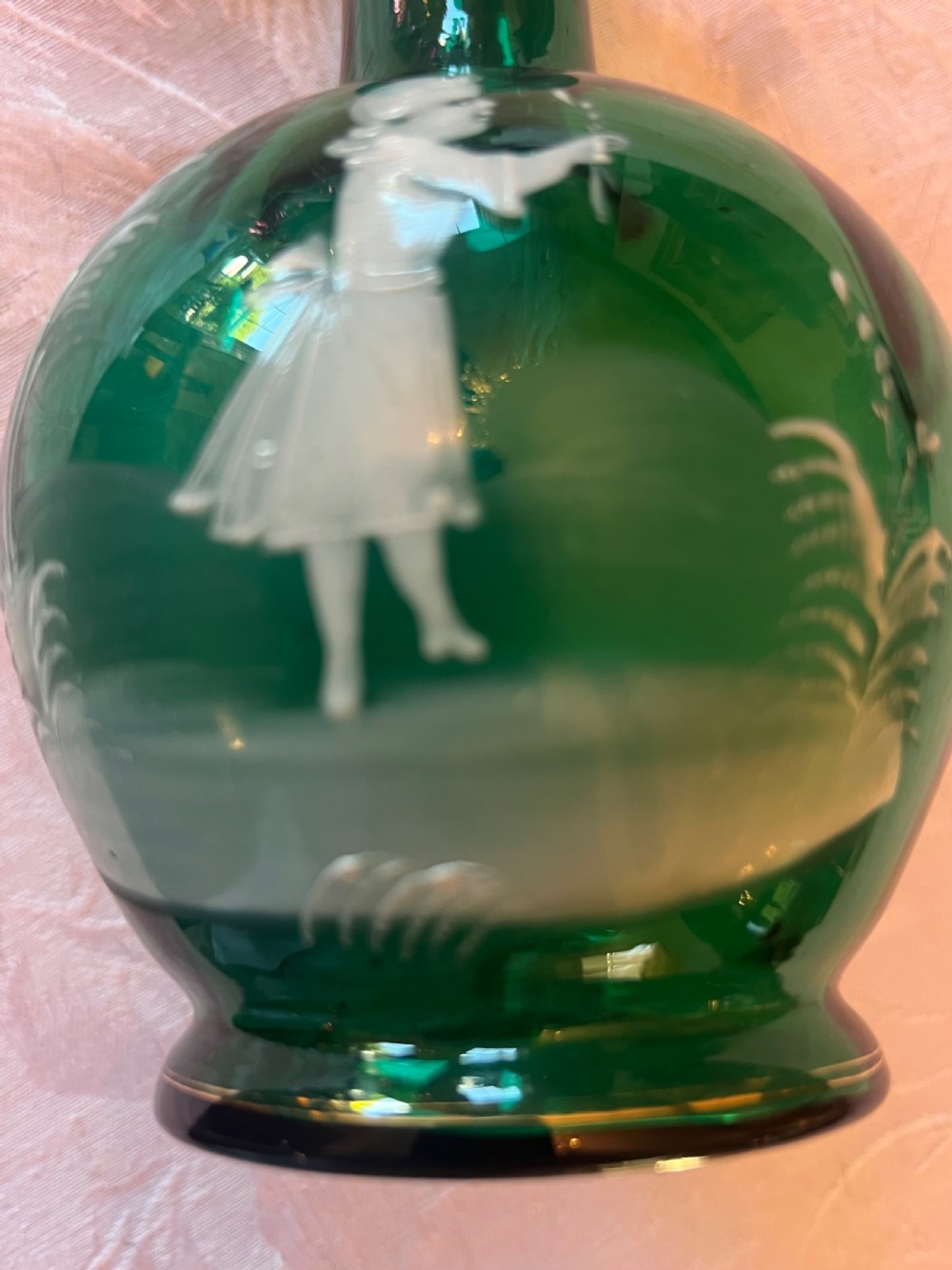 An emerald green glass vase featuring a white enamel painted scene of a child holding a plant sprig. View III