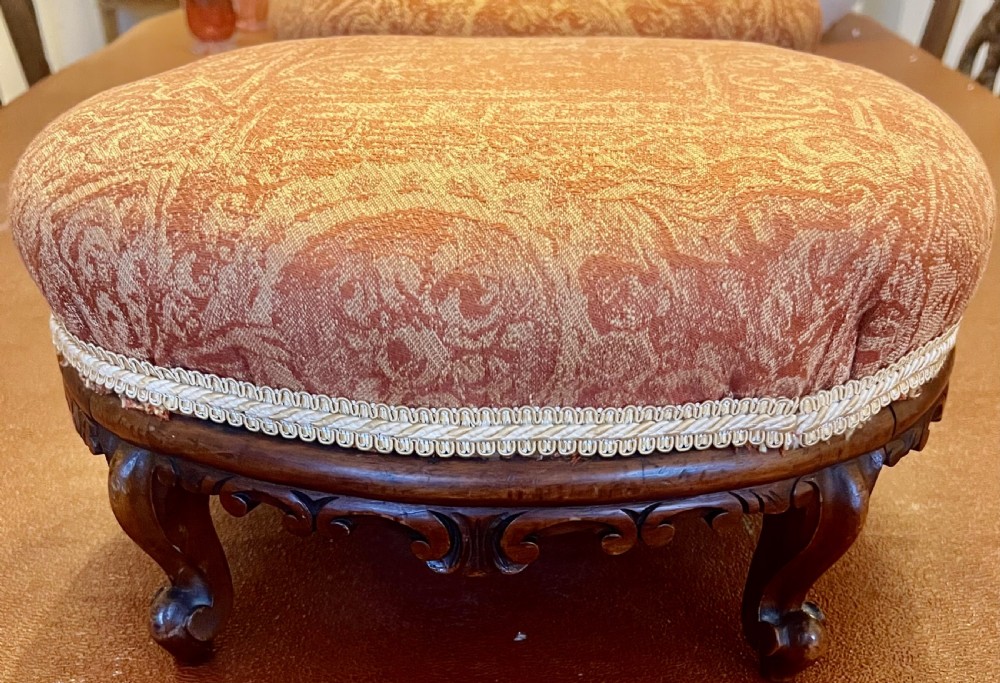 A matching pair of low circular Victorian footstools with patterned orange upholstery, decorative braid trim, and dark carved wooden legs. View VIII