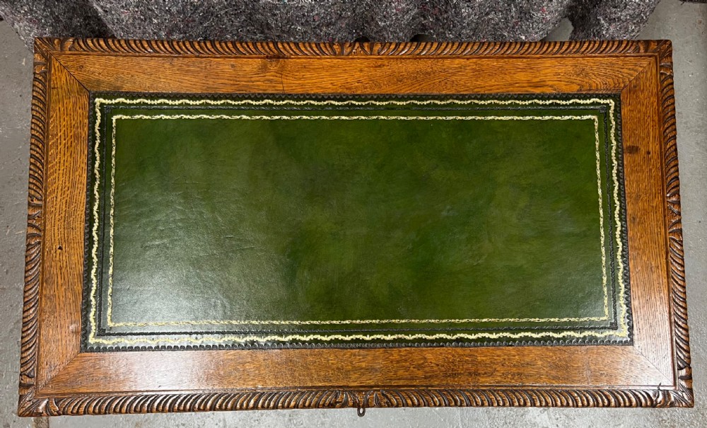A 19th-century carved oak writing table featuring a green leather inset top, carved frieze, barley twist legs, and a central stretcher with finial. View III