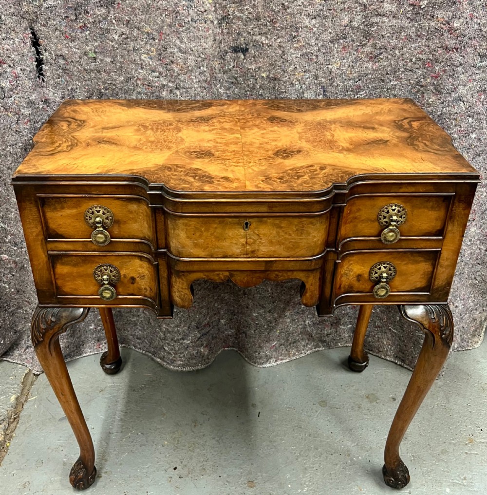 A burr walnut lowboy side table featuring five drawers, brass drop handles, a shaped apron, and four cabriole legs.
