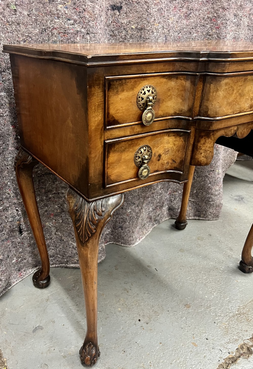 A burr walnut lowboy side table featuring five drawers, brass drop handles, a shaped apron, and four cabriole legs. View V
