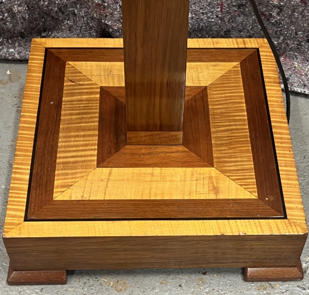 An Art Deco wooden standard lamp featuring a square column with contrasting inlaid bands set upon a stepped, multi-toned geometric base. View II