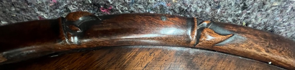 An oval brown hardwood coffee table with carved faux bamboo trim on a folding base. View V
