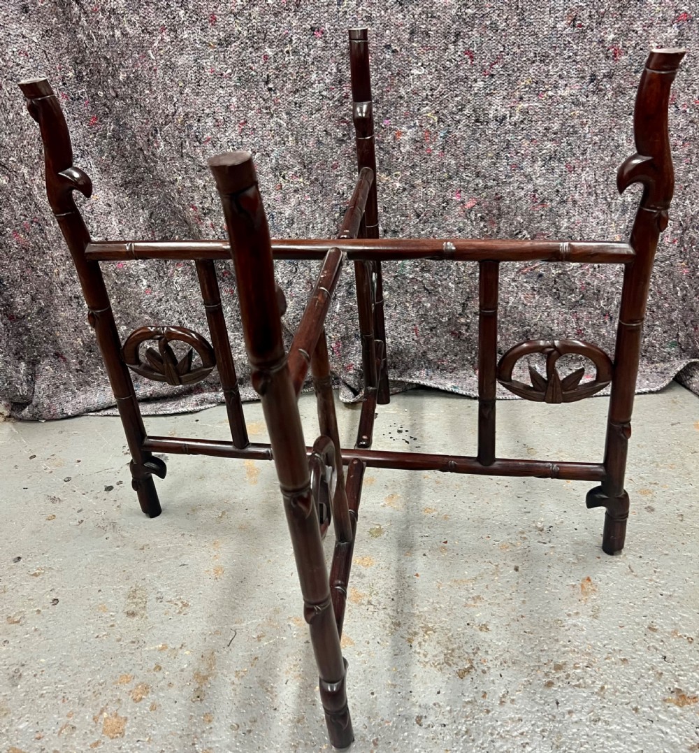 An oval brown hardwood coffee table with carved faux bamboo trim on a folding base. View VI
