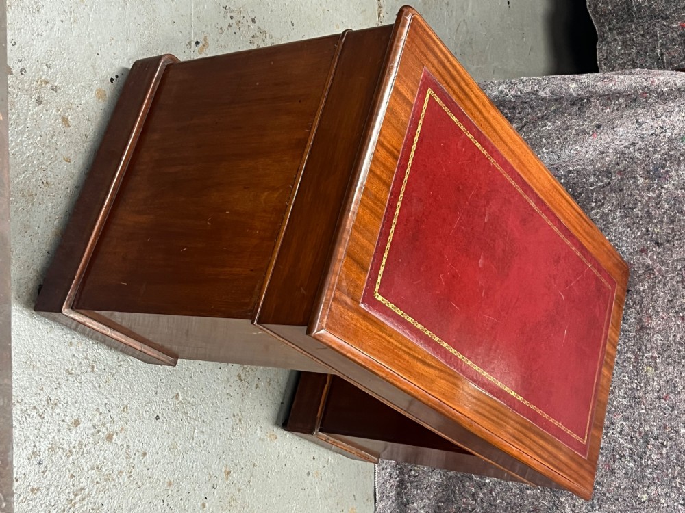 A compact Victorian mahogany pedestal desk featuring a red leather inset top, nine drawers with brass handles, and a plinth base on castors. View VII