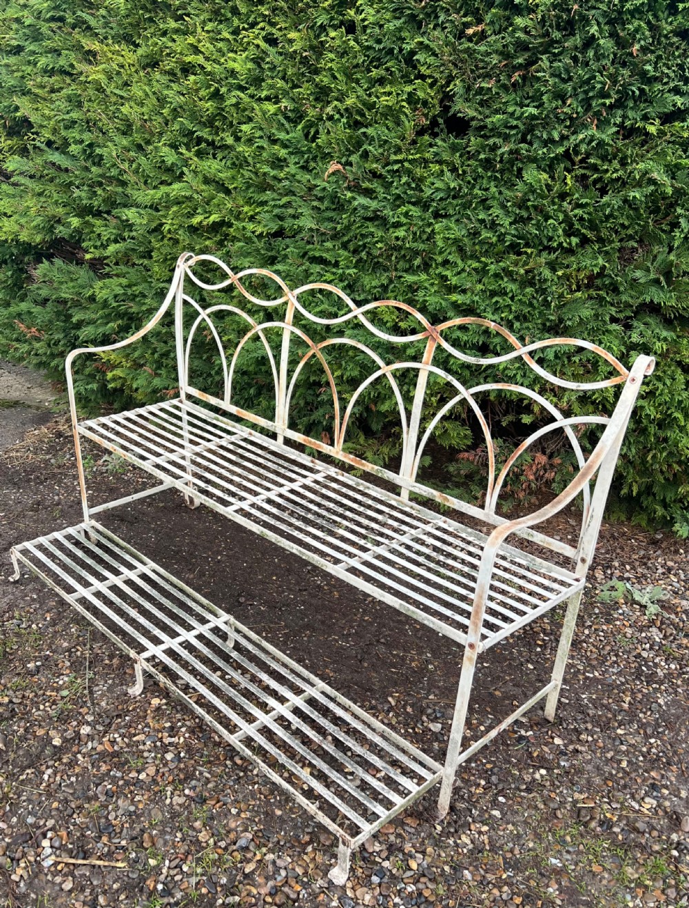 An off-white painted wrought iron garden seat featuring slatted strapwork construction, gothic backrest arches, and a lower footrest with weathered patina. View II