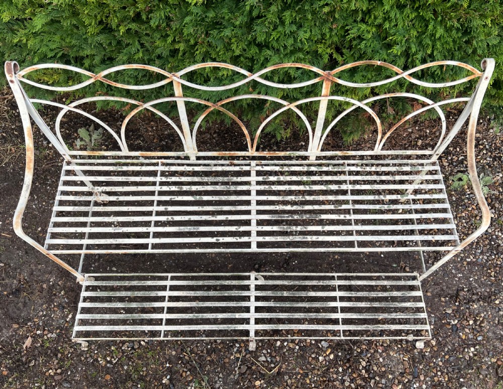 An off-white painted wrought iron garden seat featuring slatted strapwork construction, gothic backrest arches, and a lower footrest with weathered patina. View IV