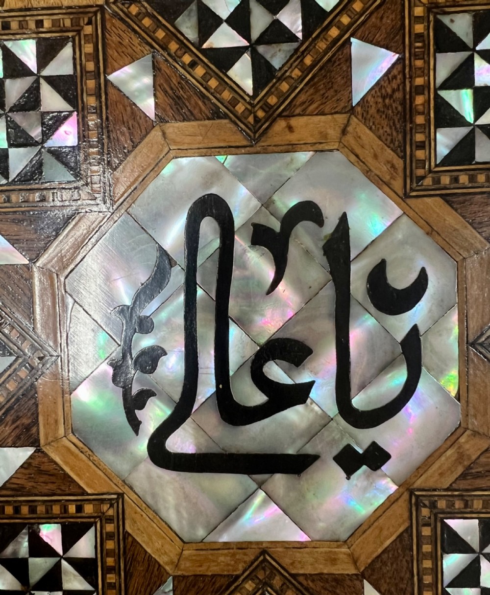 An octagonal wooden side table decorated with intricate mother-of-pearl, bone, and marquetry geometric patterns and central Arabic calligraphy. View IV