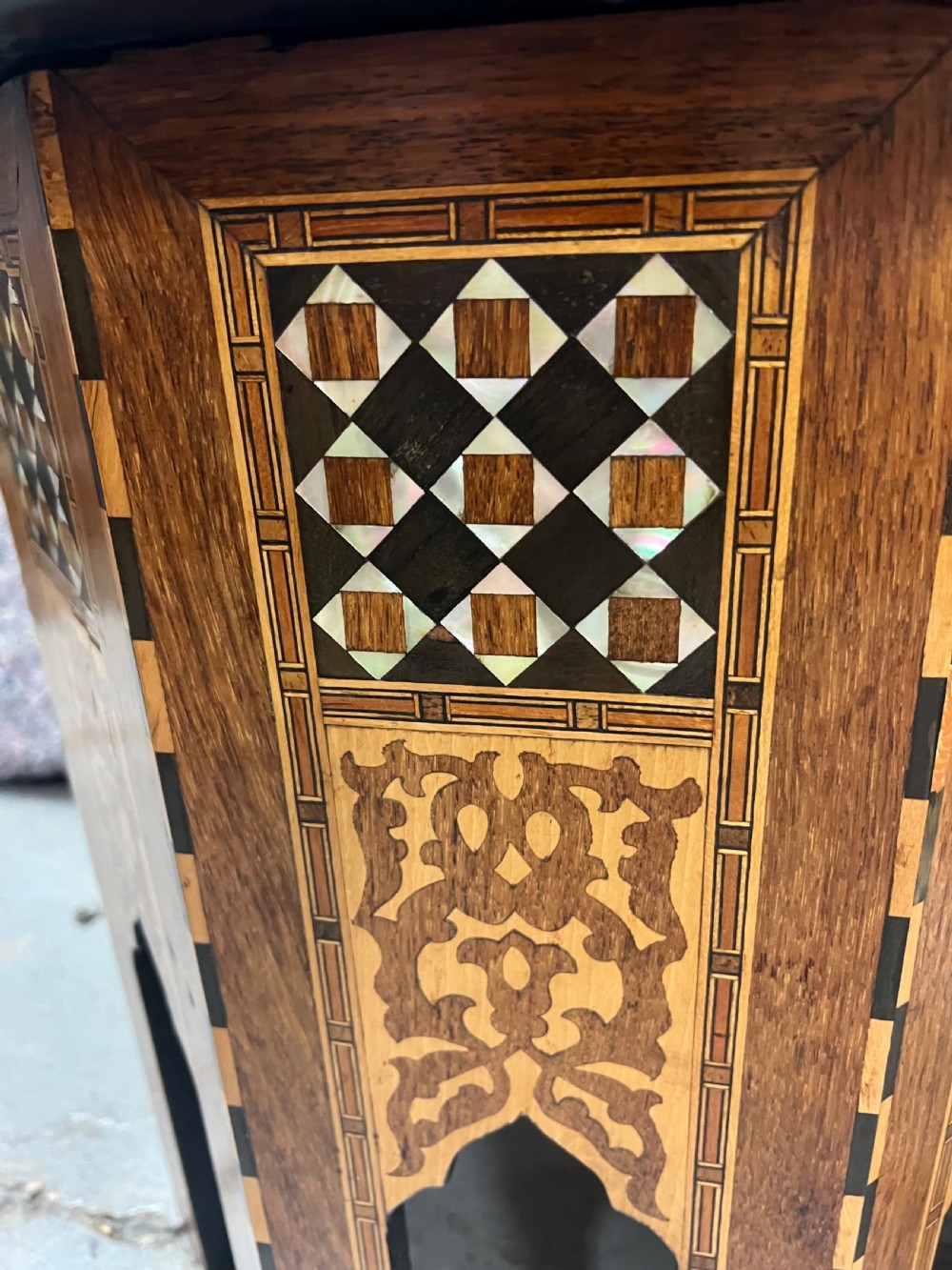 An octagonal wooden side table decorated with intricate mother-of-pearl, bone, and marquetry geometric patterns and central Arabic calligraphy. View V