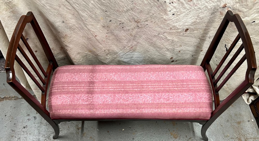 An Edwardian mahogany window seat with slatted side armrests, curved legs, and a pink patterned upholstered cushion. View III