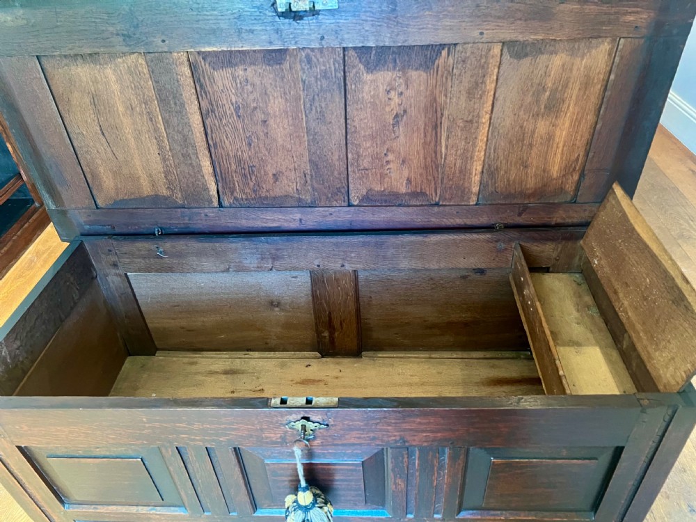 An eighteenth-century dark oak mule chest featuring a four-panel hinged lid, fielded panel front, and two lower drawers with brass drop handles. View VII