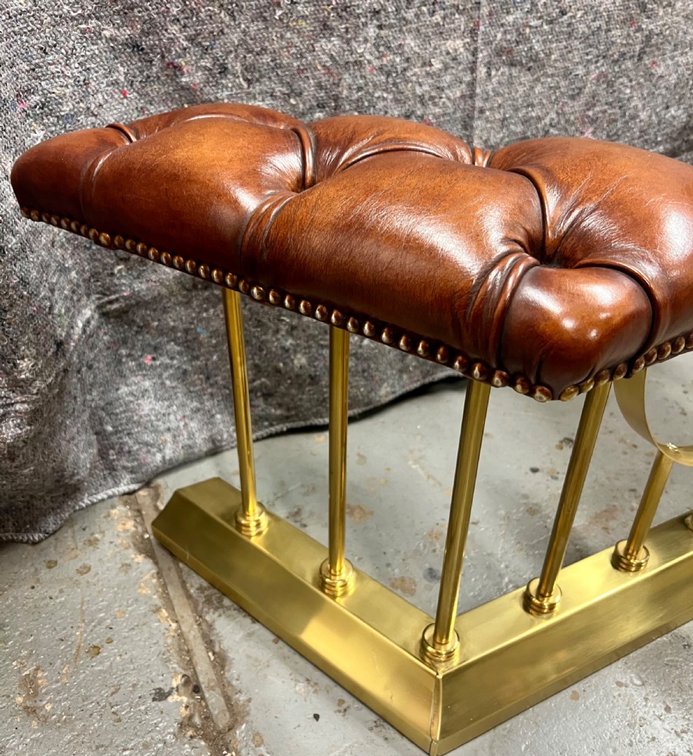 A brass fireplace club fender featuring two deep-buttoned brown leather seats supported by vertical brass spindles on a shaped metal base. View VI