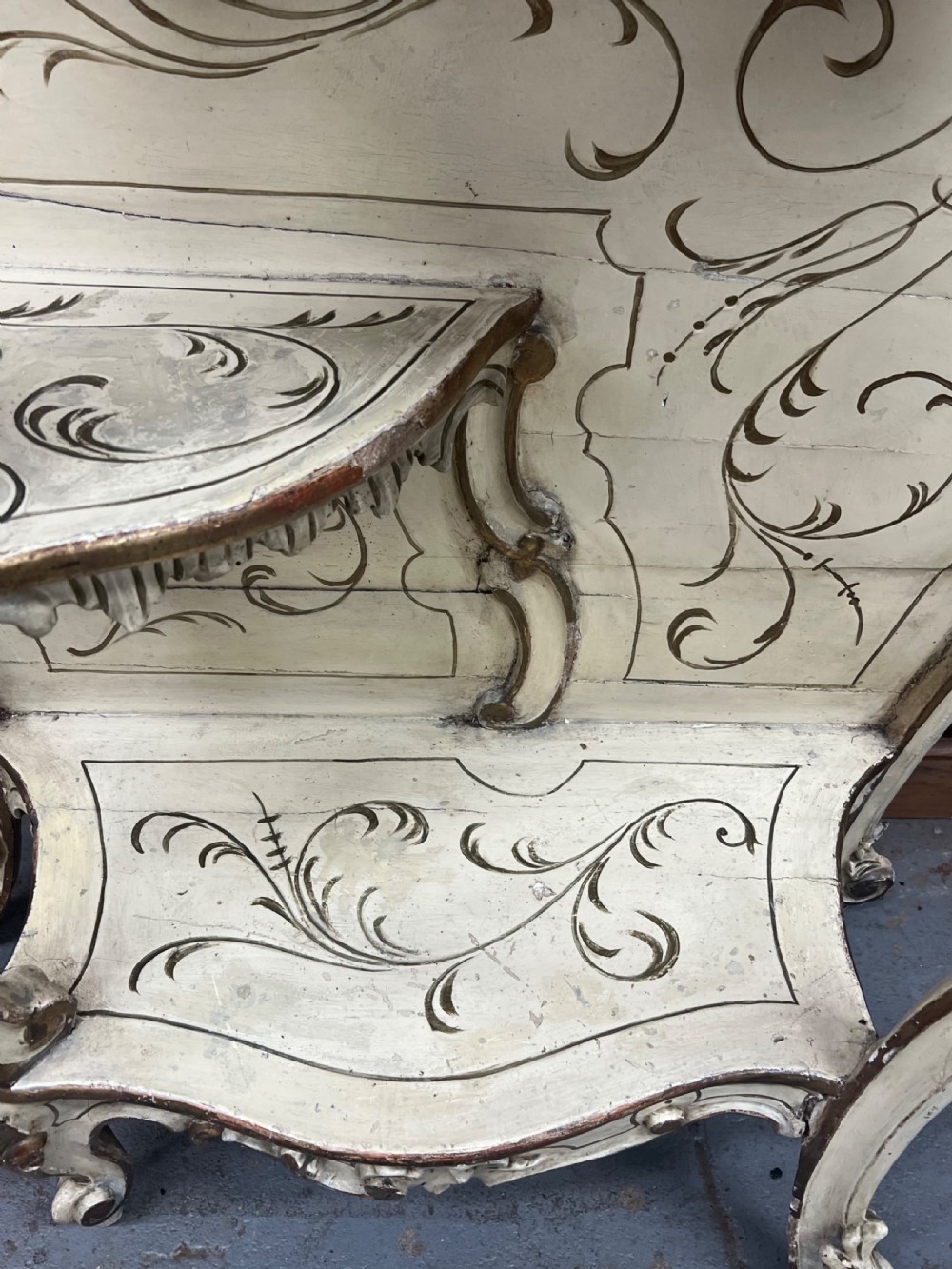 An ornate cream-painted and parcel-gilt Venetian Rococo console table featuring an asymmetrical tall mirror, tiered display shelves, and scrolling cabriole legs. View X