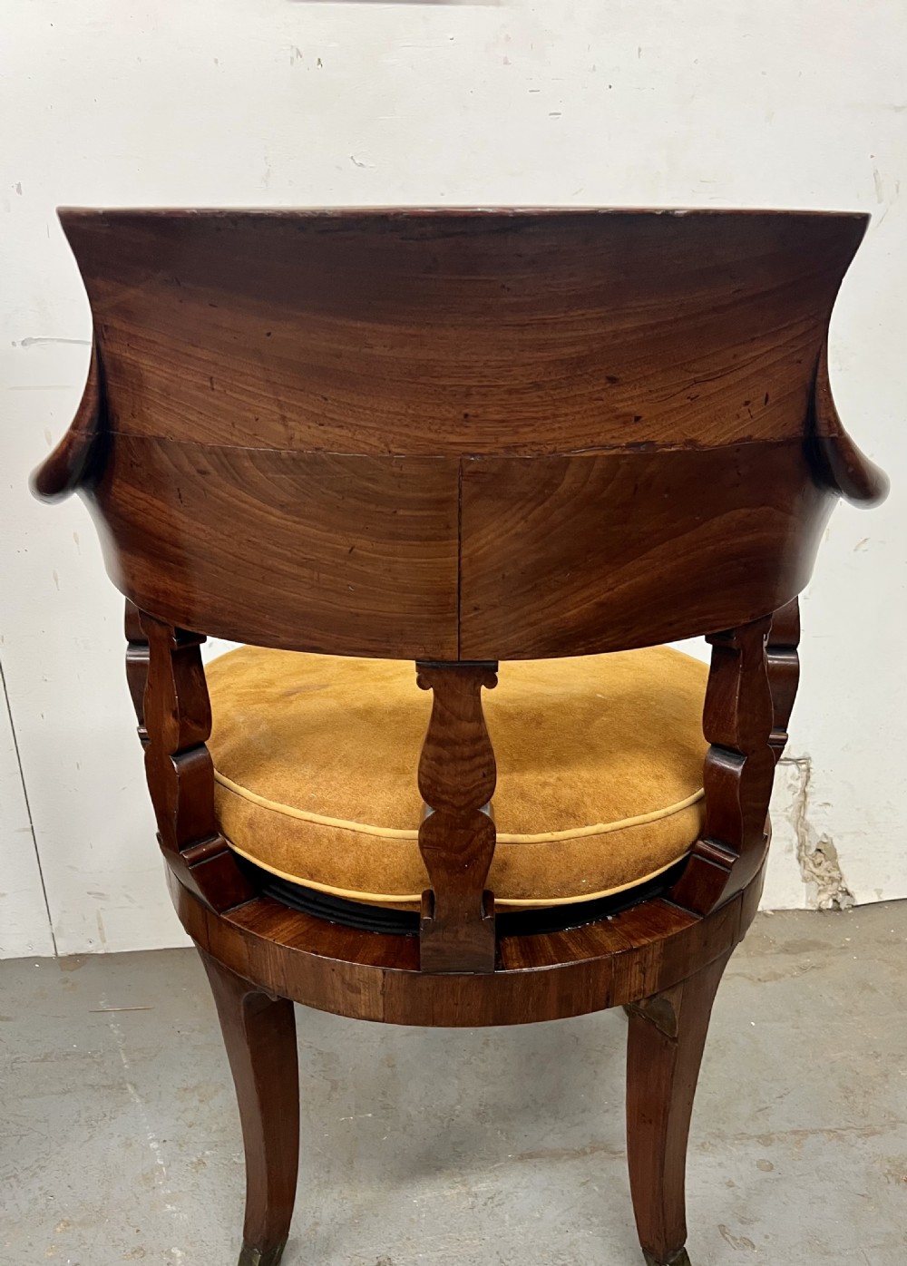 A Victorian mahogany revolving desk chair featuring a curved horseshoe backrest, carved support splats, tan suede upholstered seat, and cabriole-style legs on brass castors. View IV