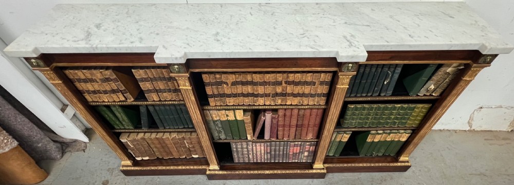 A low three-bay Regency style rosewood open bookcase with a white marble top, fluted gilded pilasters, and carved lion head mounts. View IV