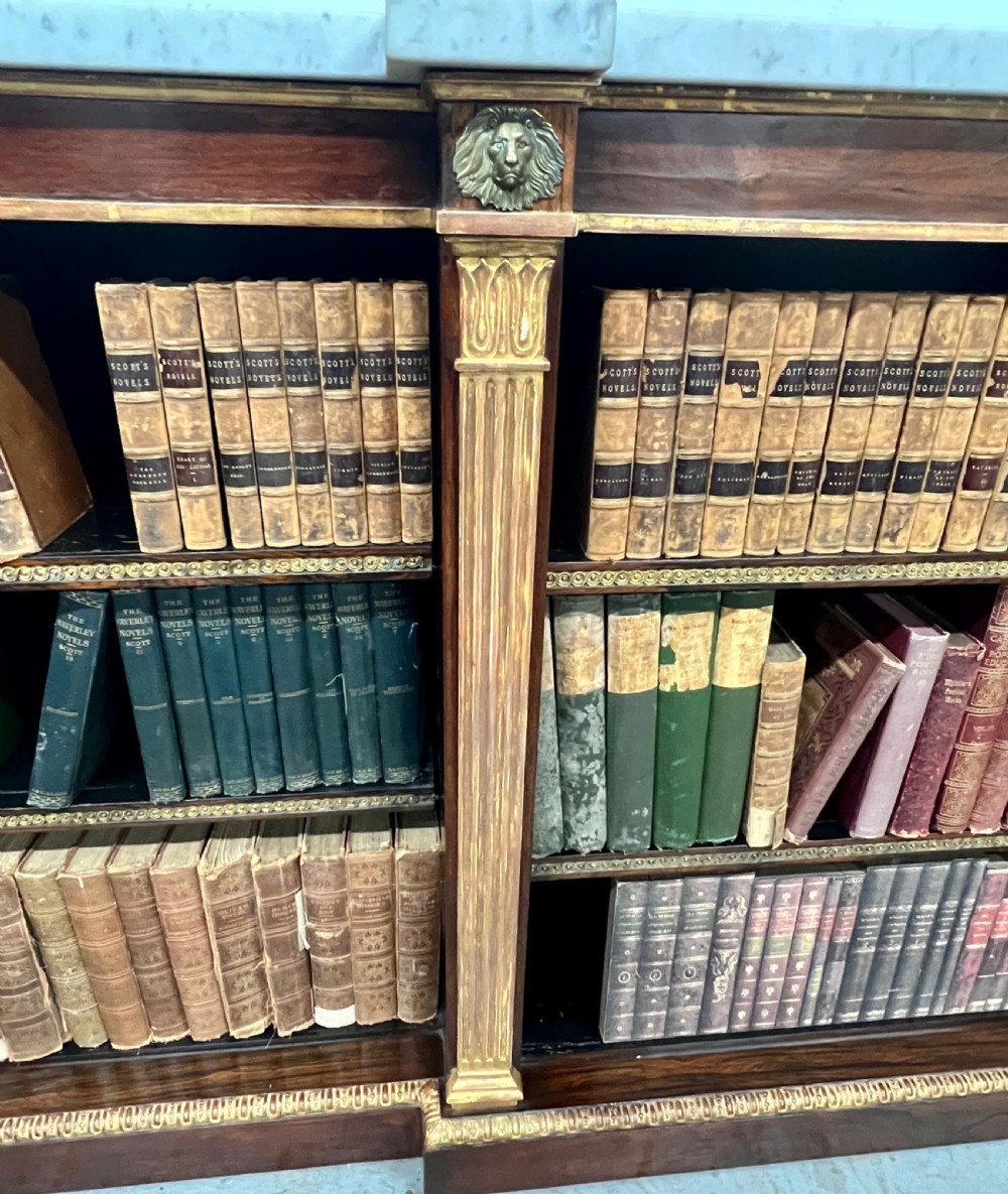 A low three-bay Regency style rosewood open bookcase with a white marble top, fluted gilded pilasters, and carved lion head mounts. View VII