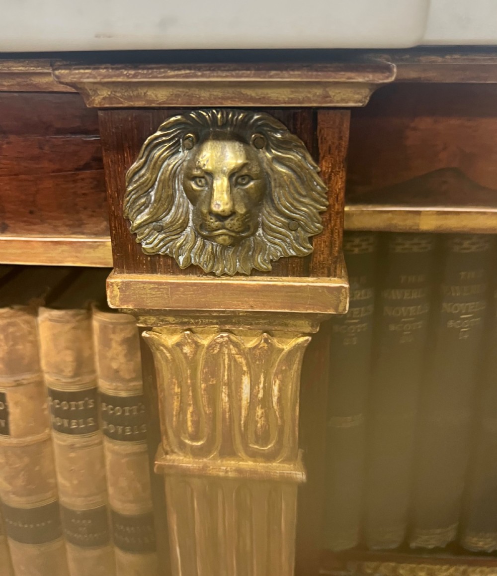 A low three-bay Regency style rosewood open bookcase with a white marble top, fluted gilded pilasters, and carved lion head mounts. View VIII