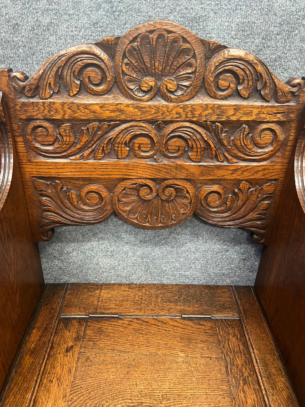 An antique carved oak hall stand set featuring a top wall-mounted mirror with coat pegs and a matching lower bench with integrated umbrella holders. View V