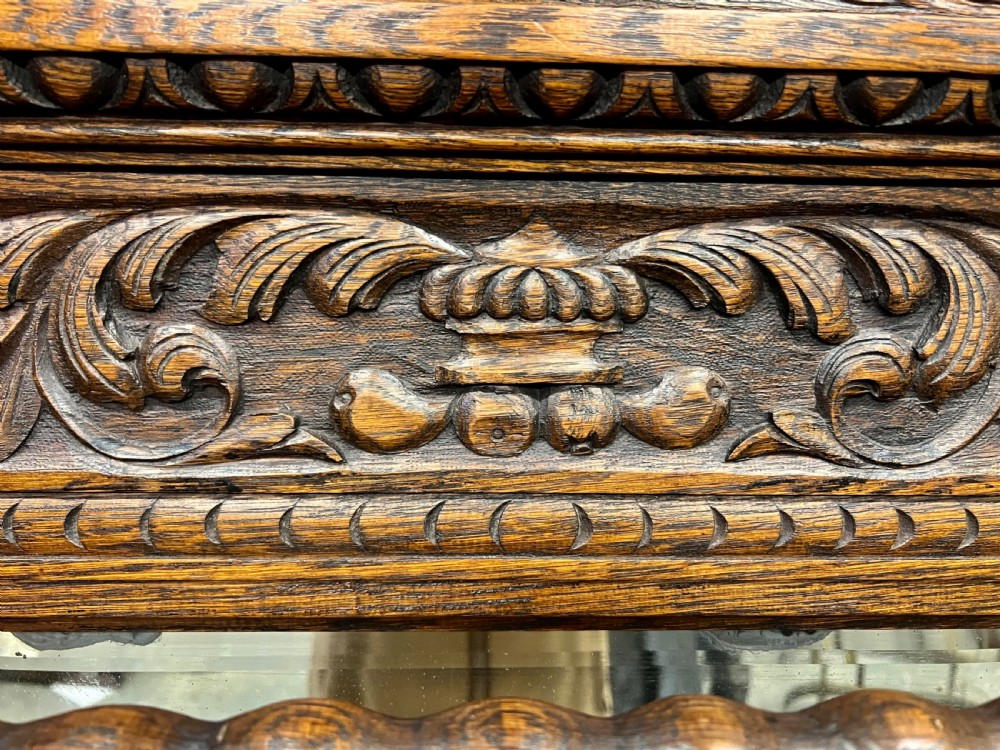 An antique carved oak hall stand set featuring a top wall-mounted mirror with coat pegs and a matching lower bench with integrated umbrella holders. View VI