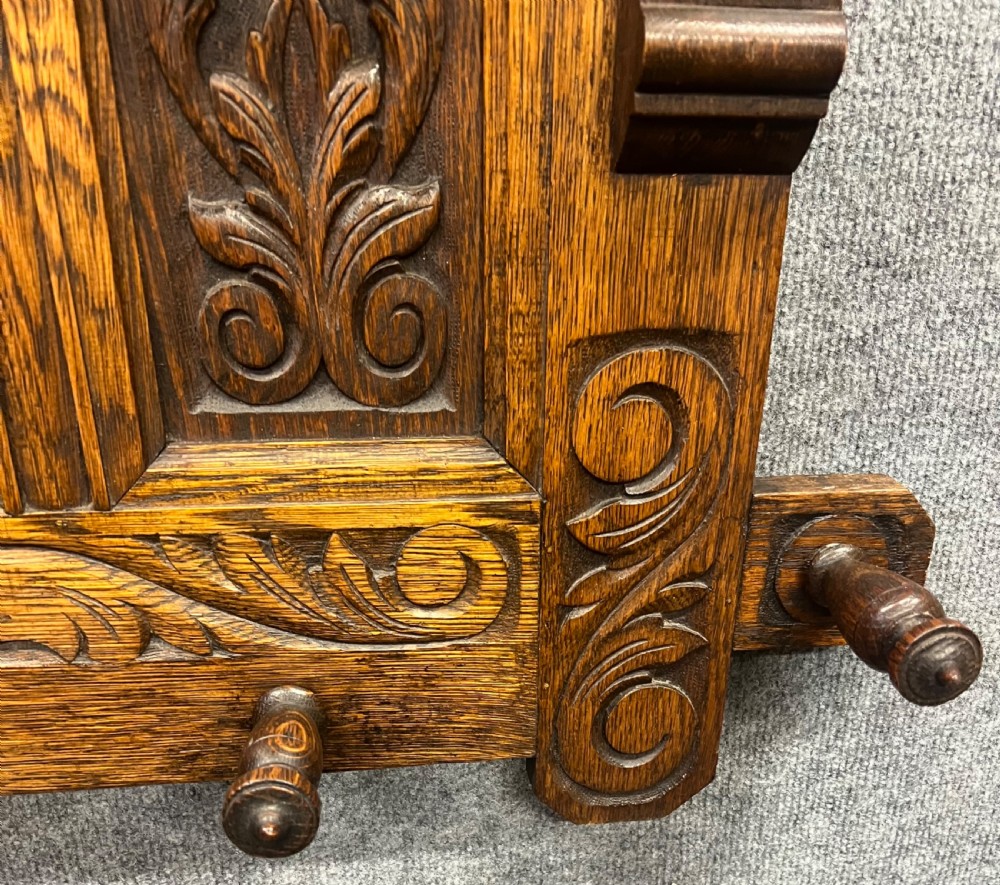 An antique carved oak hall stand set featuring a top wall-mounted mirror with coat pegs and a matching lower bench with integrated umbrella holders. View VII