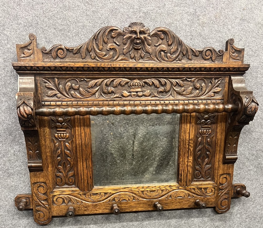 An antique carved oak hall stand set featuring a top wall-mounted mirror with coat pegs and a matching lower bench with integrated umbrella holders. View XII