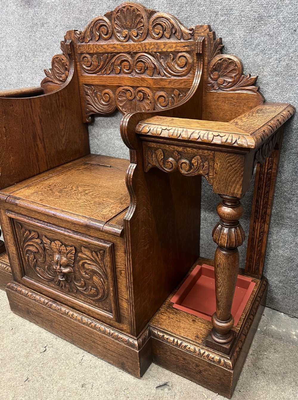 An antique carved oak hall stand set featuring a top wall-mounted mirror with coat pegs and a matching lower bench with integrated umbrella holders. View XIV