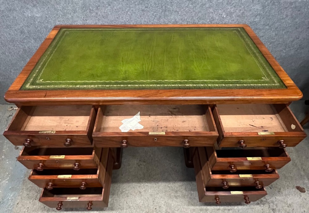 A nineteenth-century mahogany pedestal desk featuring a green leather writing top and nine drawers with turned wooden handles. View IV