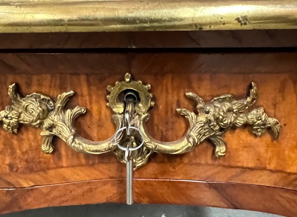 A nineteenth-century French bureau plat desk featuring wood marquetry, curved cabriole legs, ornate gilt-bronze mounts, three frieze drawers, and a leather inset writing top. View IV