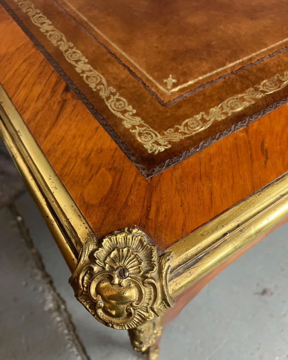 A nineteenth-century French bureau plat desk featuring wood marquetry, curved cabriole legs, ornate gilt-bronze mounts, three frieze drawers, and a leather inset writing top. View VII
