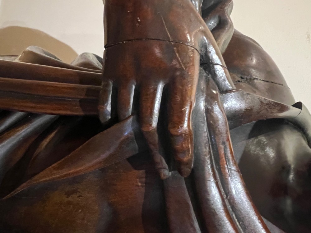 A 19th-century carved dark wood figural floor lamp depicting a draped male figure holding an illuminated flame glass urn on a octagonal base. View X