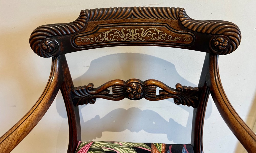 A Regency rosewood elbow chair featuring brass inlay along the top rail, curved scroll arms, a carved central splat, reeded front legs, and a colourful botanical upholstered seat. View IX