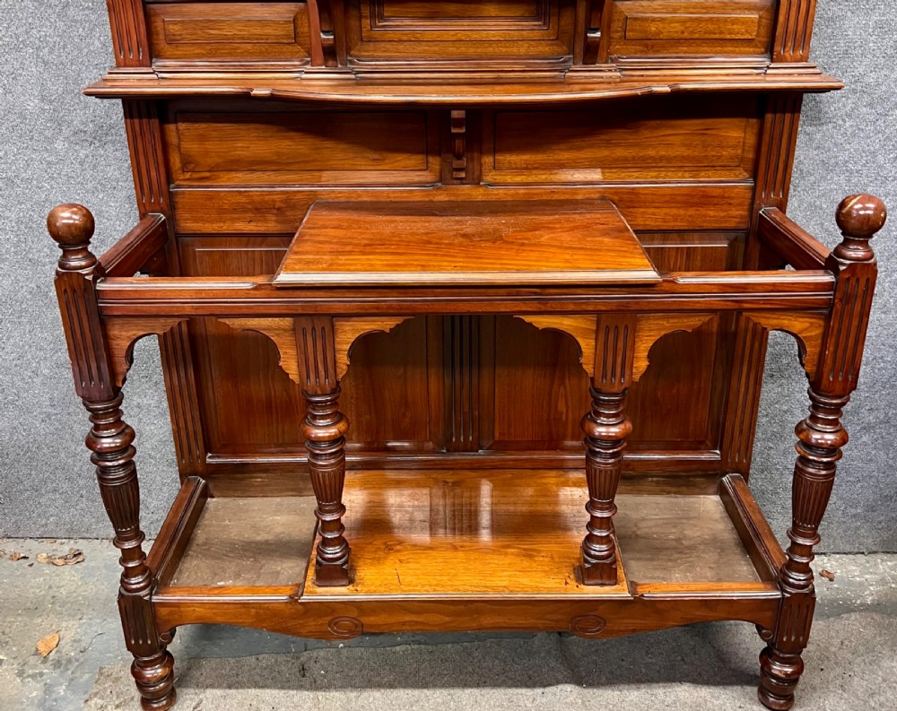 A tall Victorian carved walnut hall stand featuring brass coat hooks, bevelled mirrors, a central carved cupboard, and lower umbrella rails. View VII