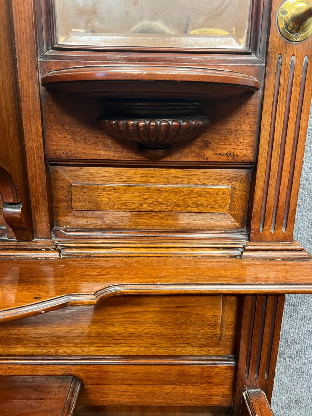 A tall Victorian carved walnut hall stand featuring brass coat hooks, bevelled mirrors, a central carved cupboard, and lower umbrella rails. View VIII