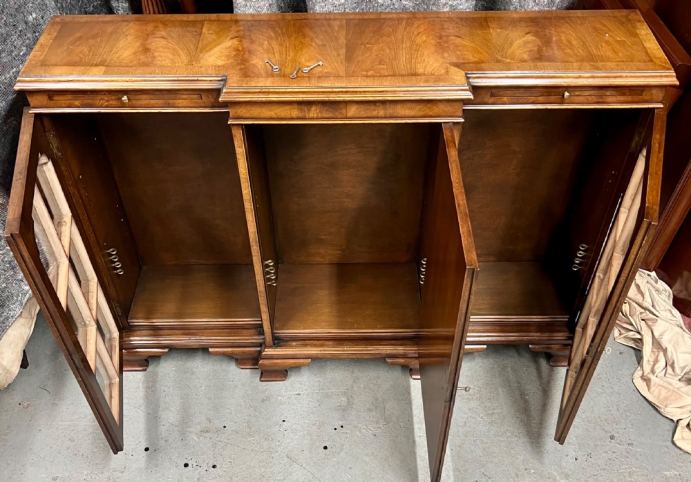 A low Queen Anne style walnut dwarf bookcase featuring a breakfront design with glazed side doors, a central veneered cupboard door, and bracket feet. View II